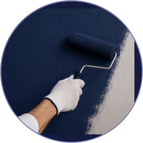A gloved hand rolling navy paint onto a wall in a clean, even line